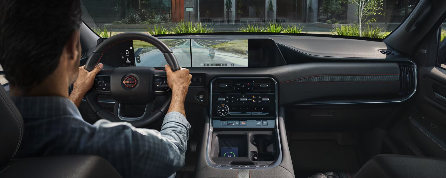 Habitacle du Nissan Armada 2025 vu depuis la place du conducteur avec écran de caméra panoramique et surpiqûres rouges visibles sur la planche de bord.