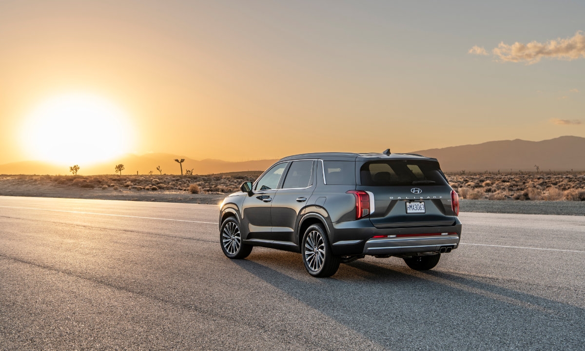 Hyundai Palisade 2023 noir vu de trois quarts arrière sur une route désertique au coucher du soleil.