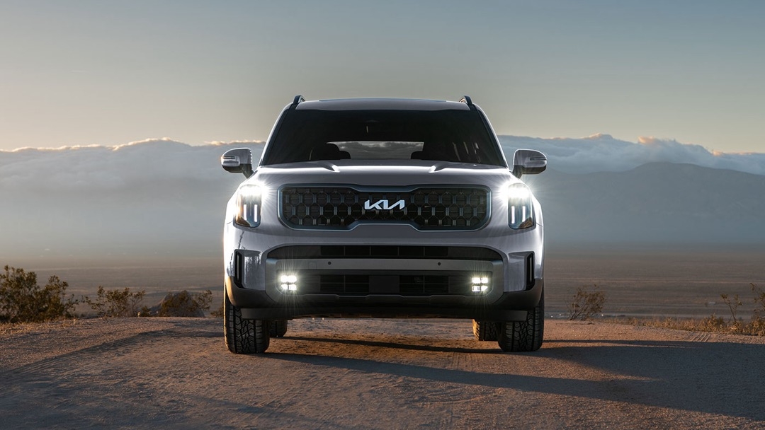 Kia Telluride 2023 gris vu de face sur une route montagneuse au lever du soleil.