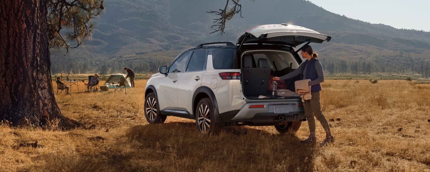 Femme chargeant le coffre du Nissan Pathfinder 2025 en nature.